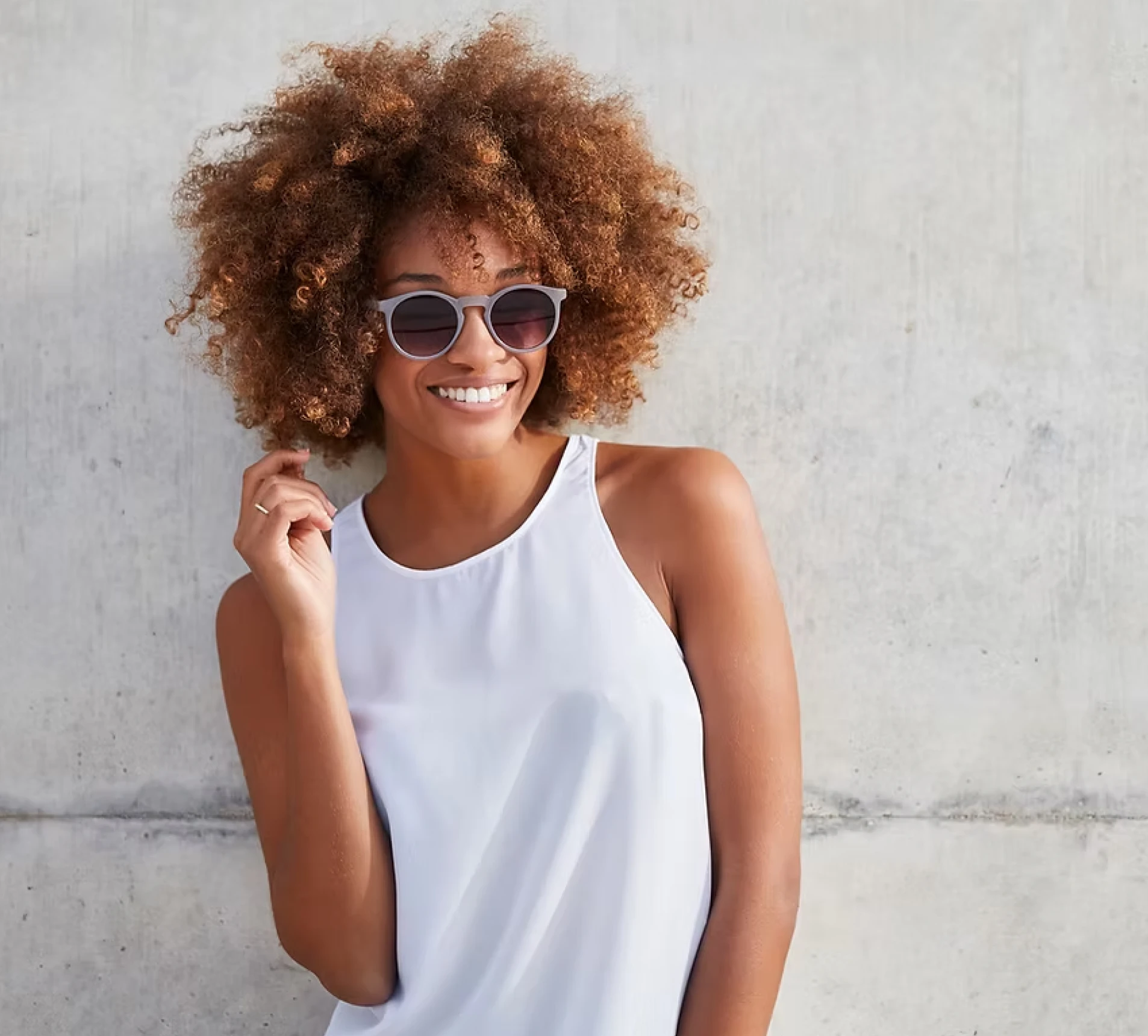 Happy woman posing against concrete wall.