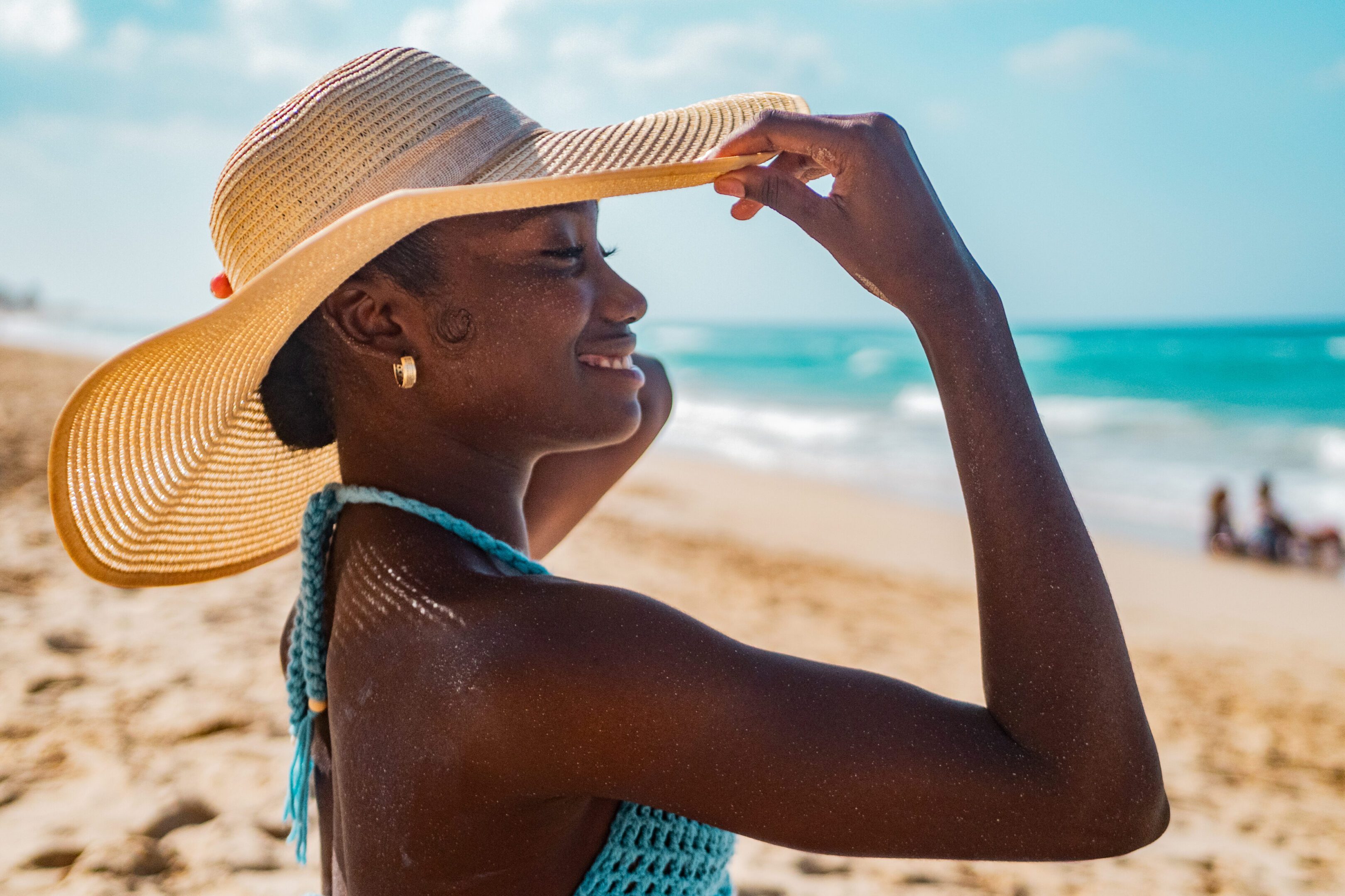 Young woman putting sun hat on the beach